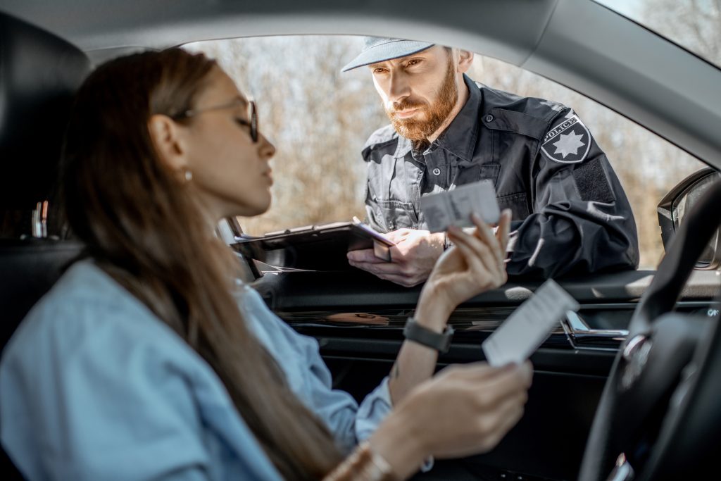 Polizist überprüft die Dokumente einer Autofahrerin bei einer Verkehrskontrolle.