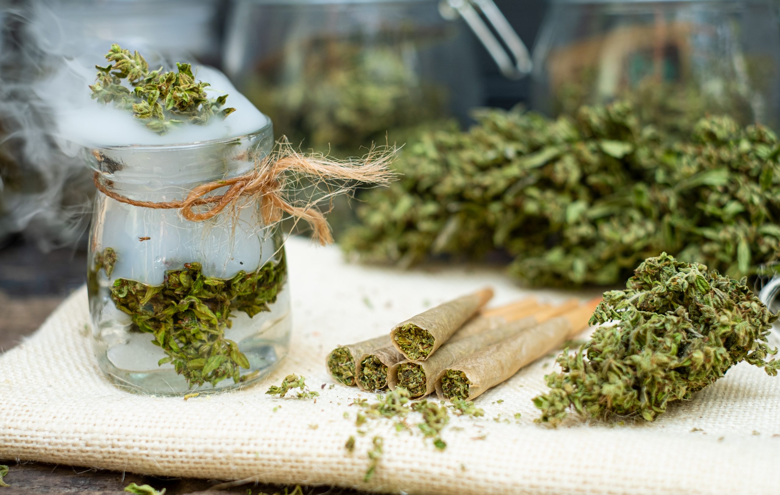 Vorgedrehte Joints mit Cannabis und getrockneten Cannabisblüten auf einem Tisch.